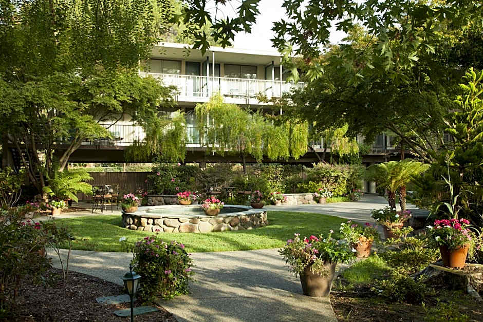 Lush garden courtyard with flowering plants, stone fountain, and outdoor seating in a peaceful residential complex; ideal for dog-friendly outdoor activities and relaxation.