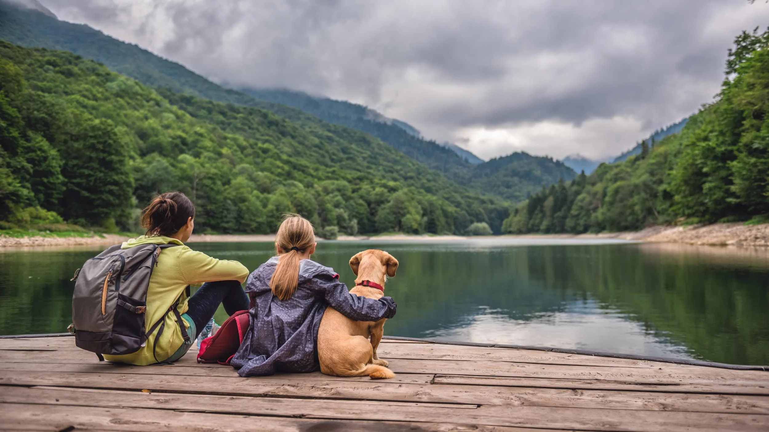 Mother and daughter with a dog resting on a pier