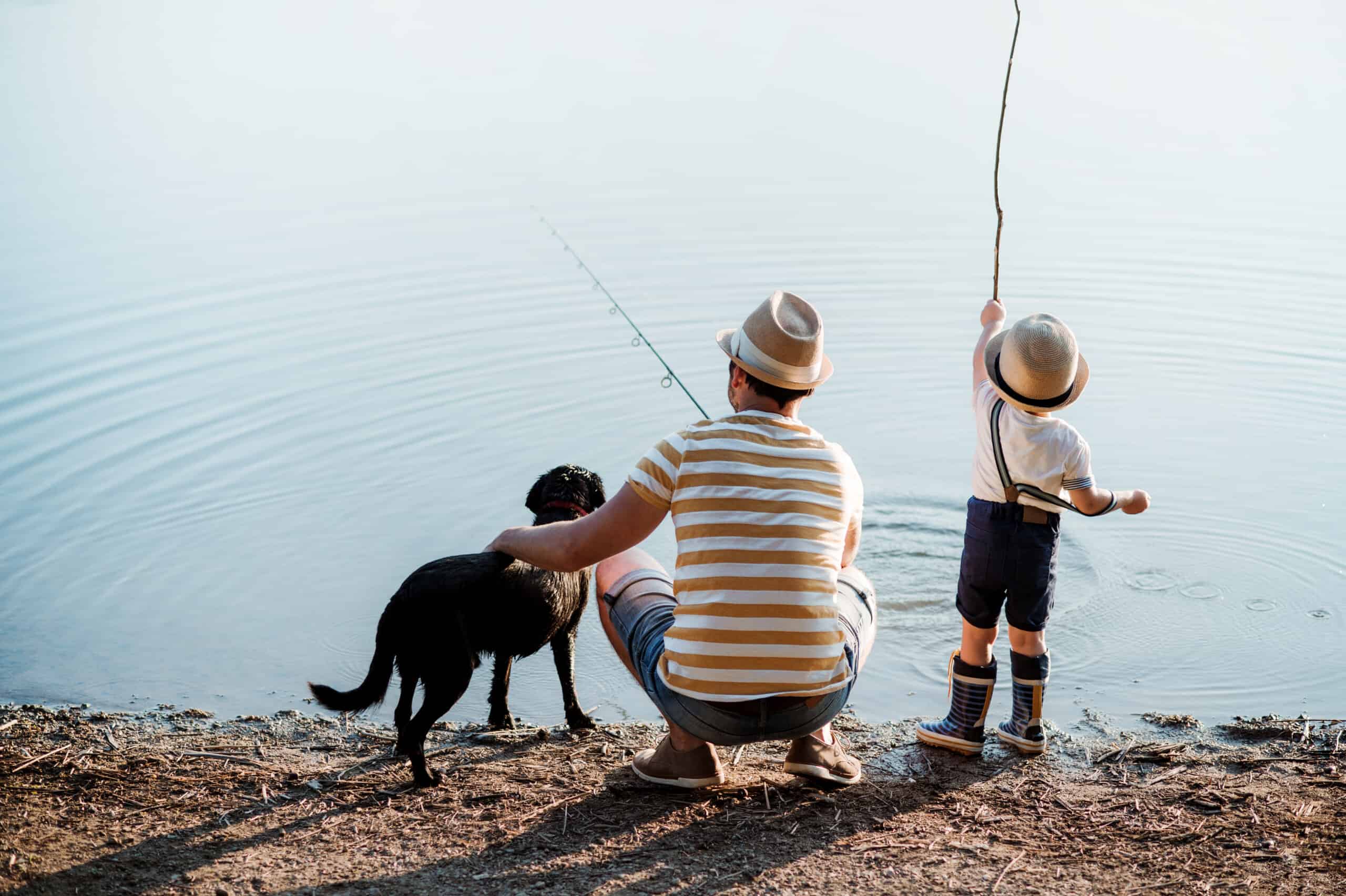 Dog and man and boy at lake fishing