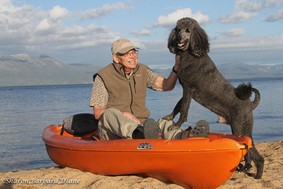 Big black standard poodle talking to person in canoe