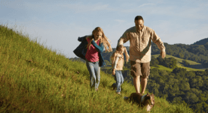 Man, woman, child and dog running on a hill