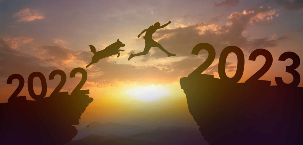 Silhouette dog and young man jumping from 2022 to 2023 at cliff
