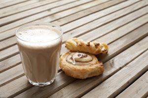 At 4 Paws Coffee Co., a glass of milk rests on a wooden table, next to a soft cinnamon roll and a twisted pastry sprinkled with almonds. This laid-back setting offers a comfortable spot to enjoy the cool milk alongside the warm, fragrant pastries.