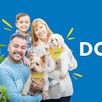 a man and a woman holding two dogs in front of a blue background.
