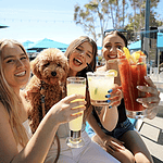 women holding cocktail with dog on outdoor patio