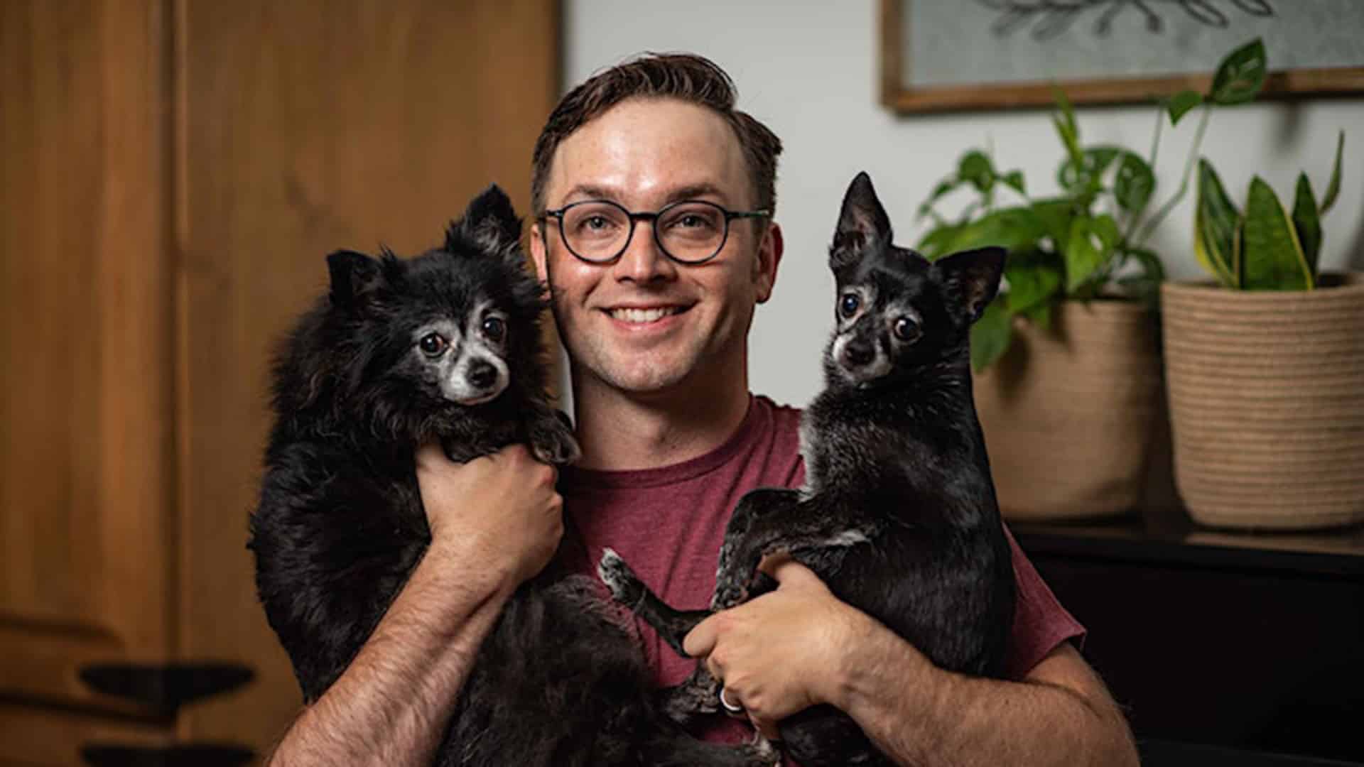 a man holding 2 dogs in his arms.