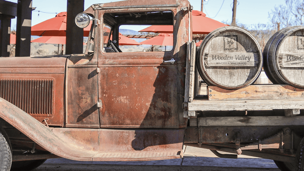 an old truck with barrels on the back of it.