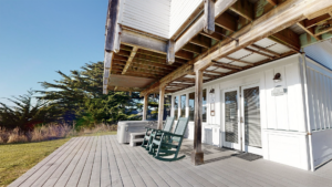 Exterior of Hannah Madison cottage showing deck with rocking chairs and a hot tub.