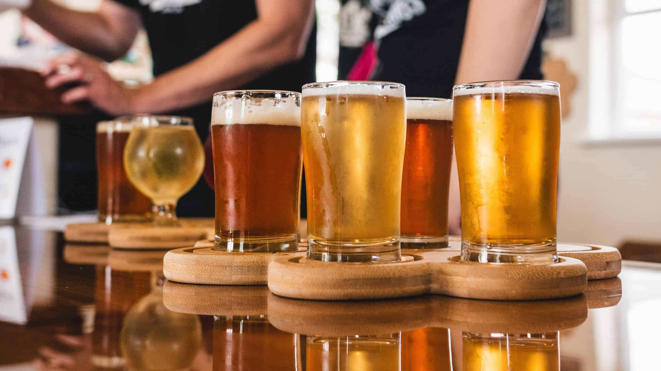 A row of beers on a wooden tray.