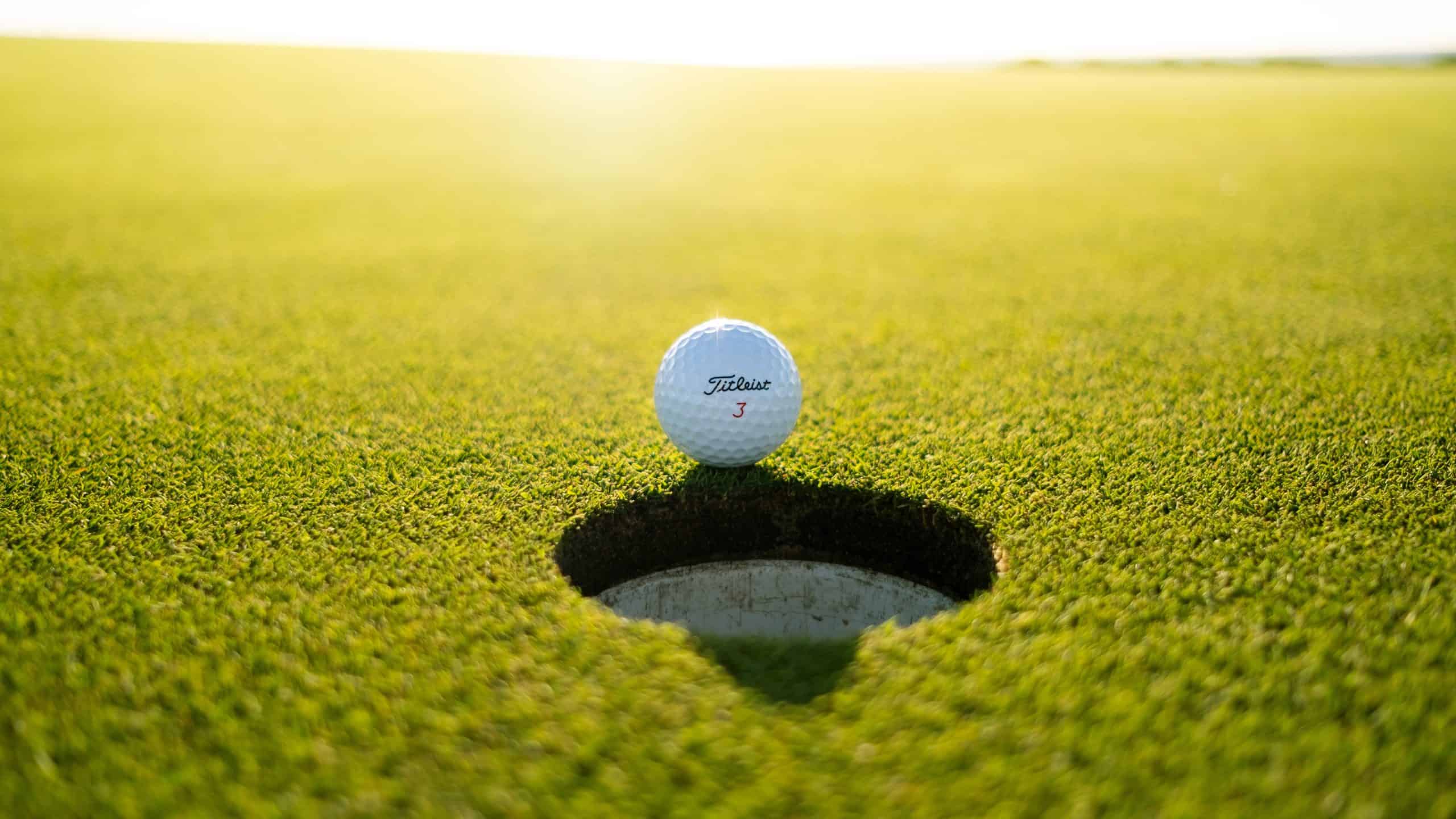 A golf ball sits in a hole on a green field.