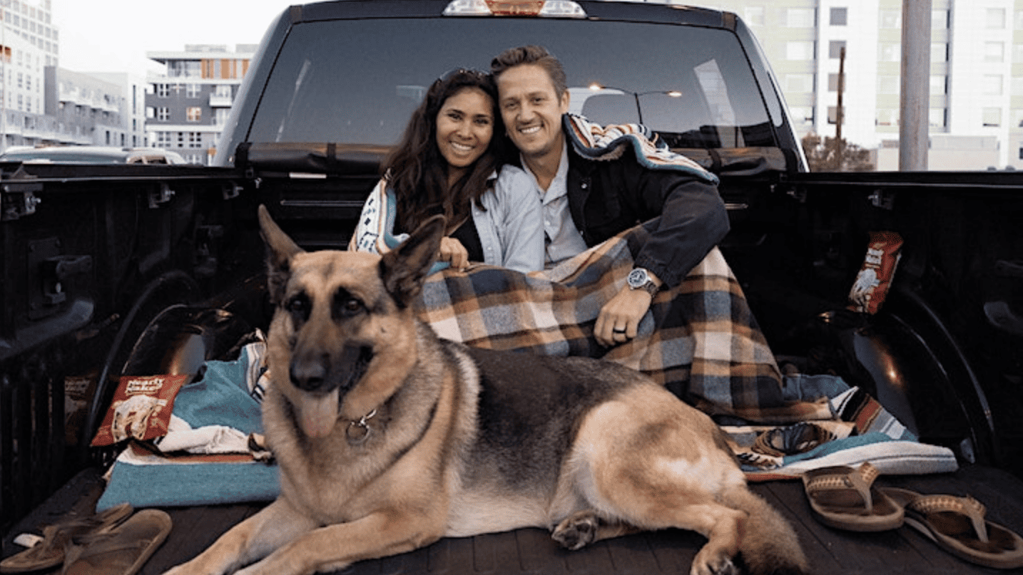couple with German shepherd dog sitting in back of pick up truck