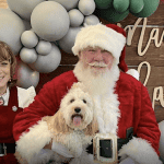 Dog poses with Santa and Mr. Claus at Small Business Holiday Market