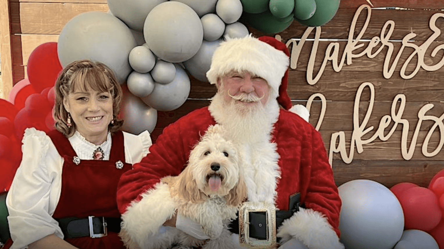 Dog poses with Santa and Mr. Claus at Small Business Holiday Market