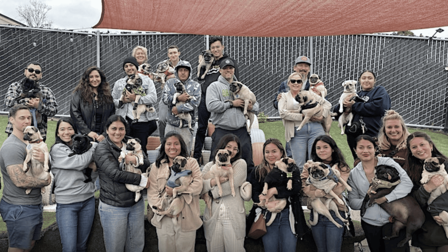 portrait of group of people holding pug dogs at The Dog Society