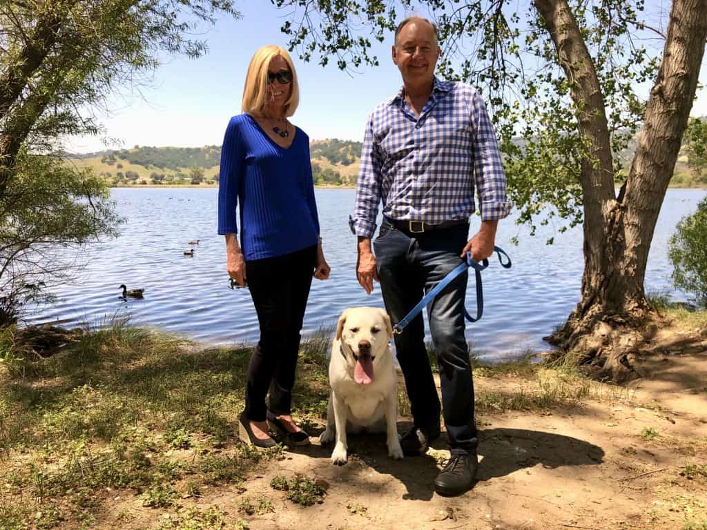 A man and woman standing next to a lake with their dog on a leash showing support for Napa Humane. - Dogtrekker