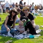 Festival goers sit on blankets on the grass with their dogs at Barks & Brews in San Diego.