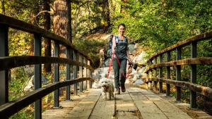 Happy woman and her excited dog hike across foot bridge
