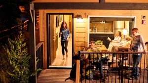 On a porch in Mariposa County, the evening air is cool and inviting. A woman emerges with a drink in hand, taking her place beside a man who is gently interacting with their black dog. The dog wags its tail cheerfully, highlighting the pet-friendly nature of the accommodations. Inside the house, another woman sits comfortably on the couch, lost in her book. Nearby, a child stands at the doorway, eyes wide with curiosity and adventure as they prepare for an evening stroll with their four-legged friend.