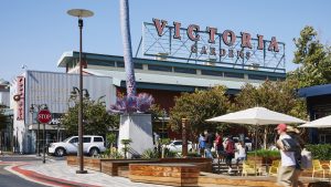 Explore the expansive outdoor shopping area at Victoria Gardens, where the atmosphere buzzes with activity and possibilities. Visitors meander along wide walkways bordered by dog-friendly patios, perfect for a leisurely outing with your four-legged friend. Bright patio umbrellas provide shade near generous planters bursting with greenery, creating inviting spots to pause during your exploration. Look for the towering "Victoria Gardens" sign that marks this vibrant locale. Don't miss a refreshing stop at "California Best Lemonade," conveniently nestled along your route, close to a noticeable "STOP" sign that punctuates the path. Tree-lined vistas stretch beneath a pristine sky, making this destination ideal for pet owners seeking enjoyable excursions in California’s beautiful weather. #GOCAL.