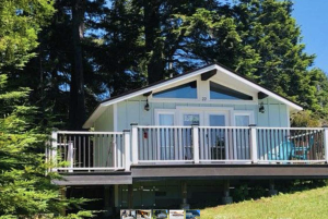 Seafoam Lodge’s cabin 22 is a compact, pale-painted structure with a private deck bordered by white railings. The deck provides direct access to a grassy area shaded by mature trees, offering plenty of space for dogs to relax or play. Double doors beneath the cabin number open into the interior, and the location’s setting gives quick entry to trails and outdoor areas suitable for walking dogs.