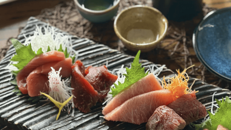 Fresh sashimi platter featuring assorted raw fish with garnishes, served on a traditional Japanese style plate, perfect for seafood lovers and Japanese cuisine enthusiasts.