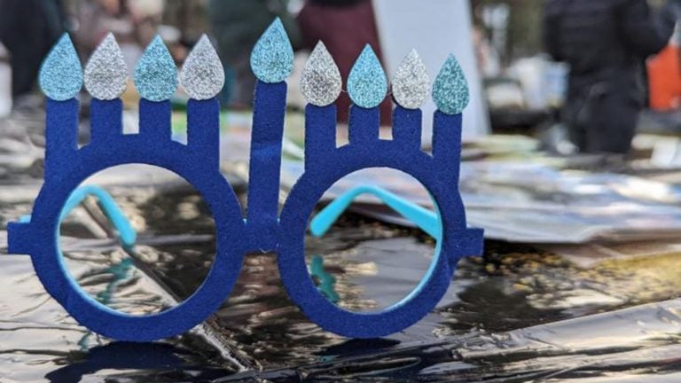 Colorful Hanukkah menorah with lit candles, celebrating Jewish holiday traditions.