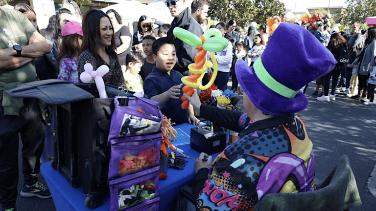 Colorful balloon artist entertaining children at outdoor festival, surrounded by excited attendees and families, showcasing community events and family-friendly activities.