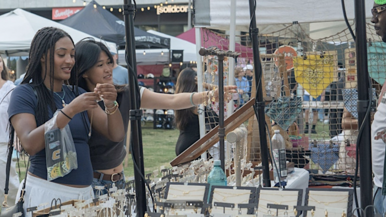 Colorful outdoor market stall selling jewelry at a lively event, with visitors browsing trendy accessories and enjoying a fun day out. Perfect for dog-friendly outdoor adventures and local shopping tips.