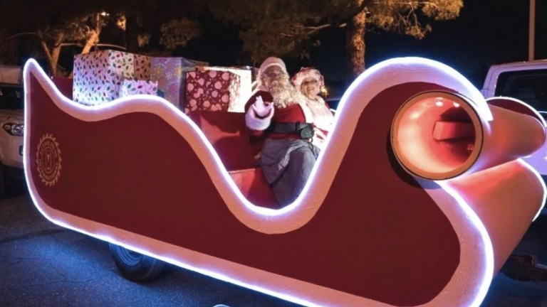 Santa and Mrs. Claus riding a festive, illuminated sleigh decorated for Christmas, creating a joyful holiday scene perfect for family theater or holiday events.