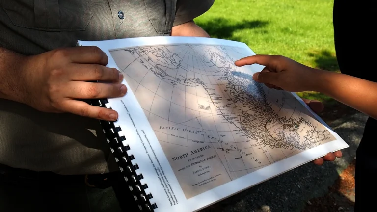 A child's hand points to a map that a ranger is holding